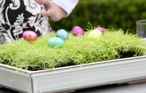 A tray of moss on a table with small glitter fake eggs for an Easter centerpiece.