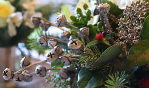A close-up of eucalyptus pods painted silver to look like jingle bells in a holiday centerpiece.