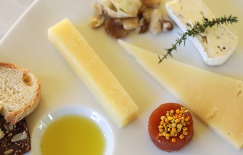close up of cheese plate with quince paste topped with bee pollen and extra virgin olive oil