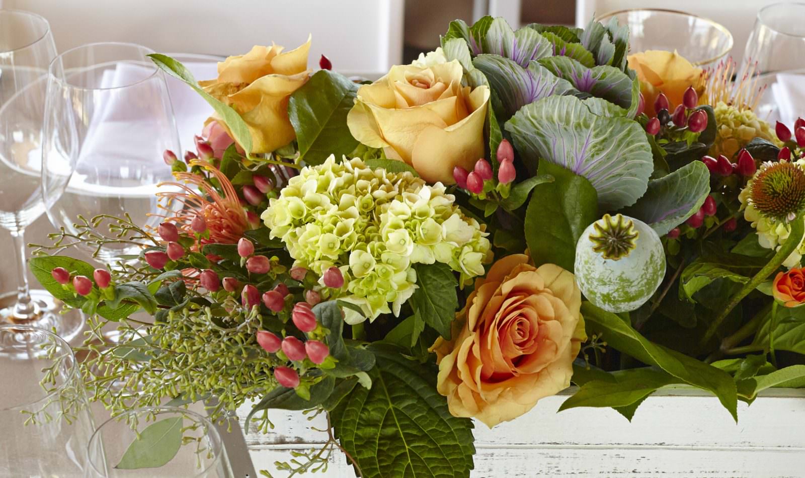 A floral arrangement with ornamental cabbage, smooth hydrangea, orange spray roses and orange flame calla lily.