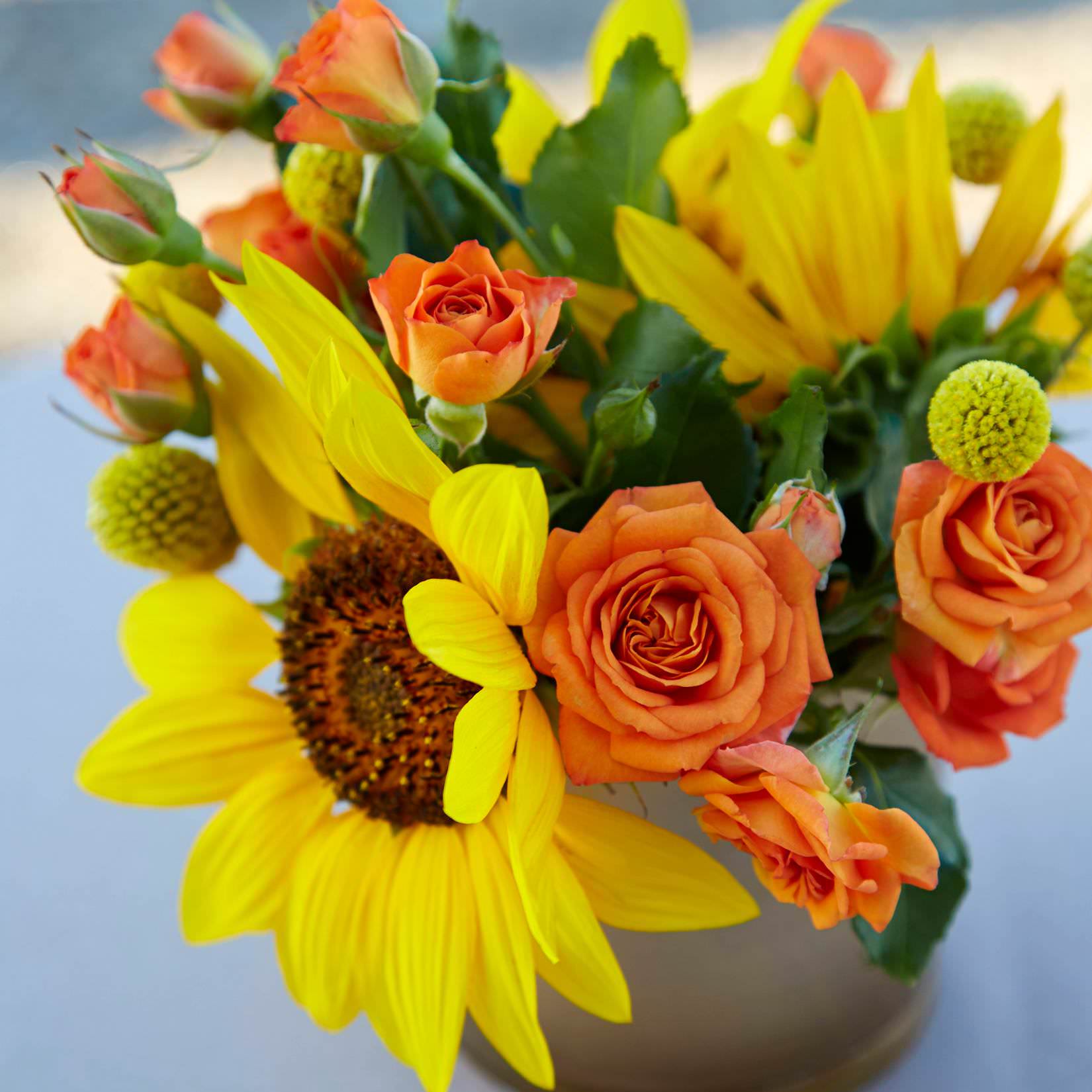 Floral centerpiece with sunflowers and orange spray roses