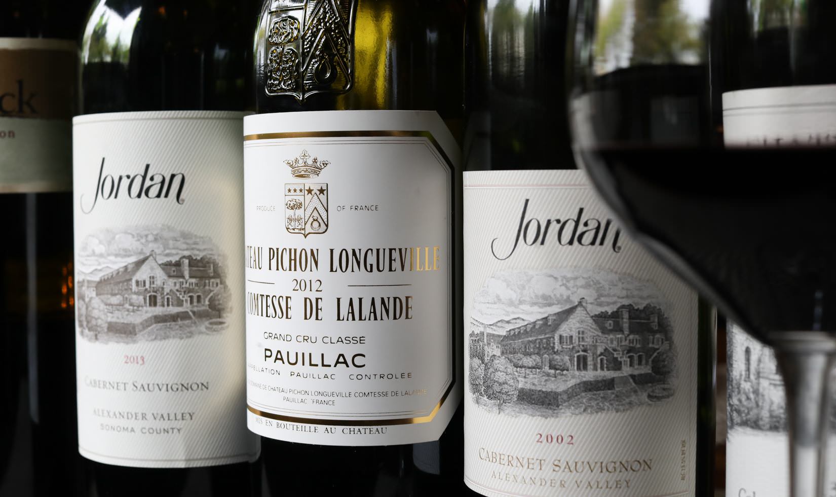 close up of bottle of 2013 Jordan Winery Cabernet, a bottle of red Bordeaux, and a bottle of 2002 Jordan Winery Cabernet