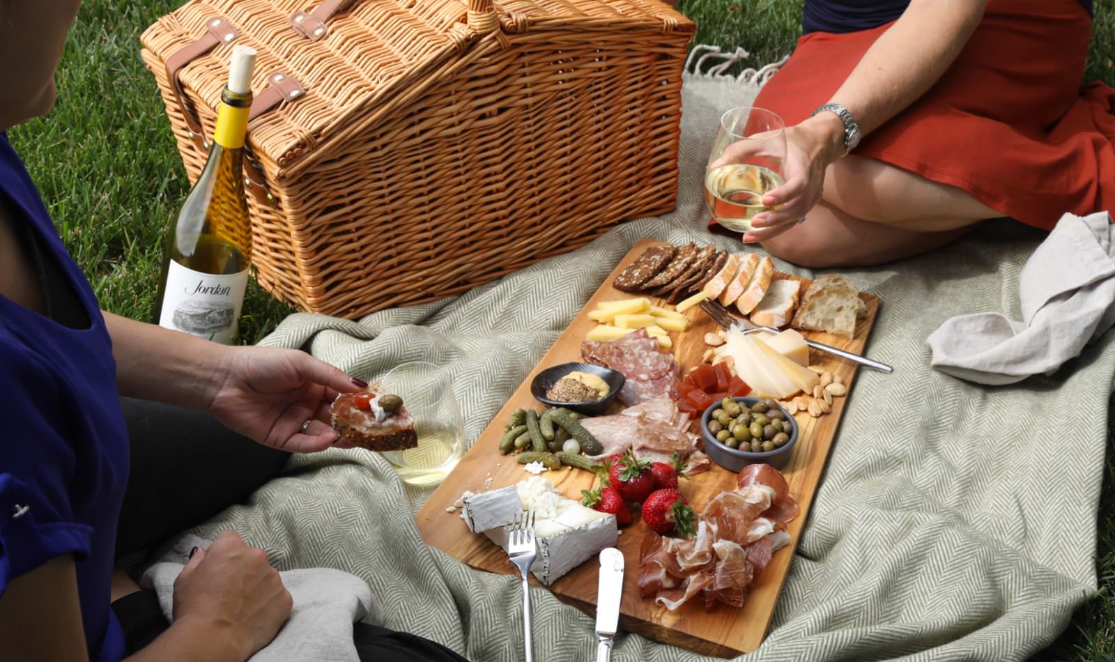 two people picnicking with a cheese and charcuterie board and Jordan Winery Chardonnay