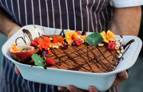 Jordan Winery chocolate mousse with edible flowers held by Jordan Winery Executive Chef Todd Knoll