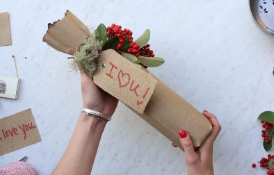 hands holding a wine bottle wrapped in paper bag and decorative berries