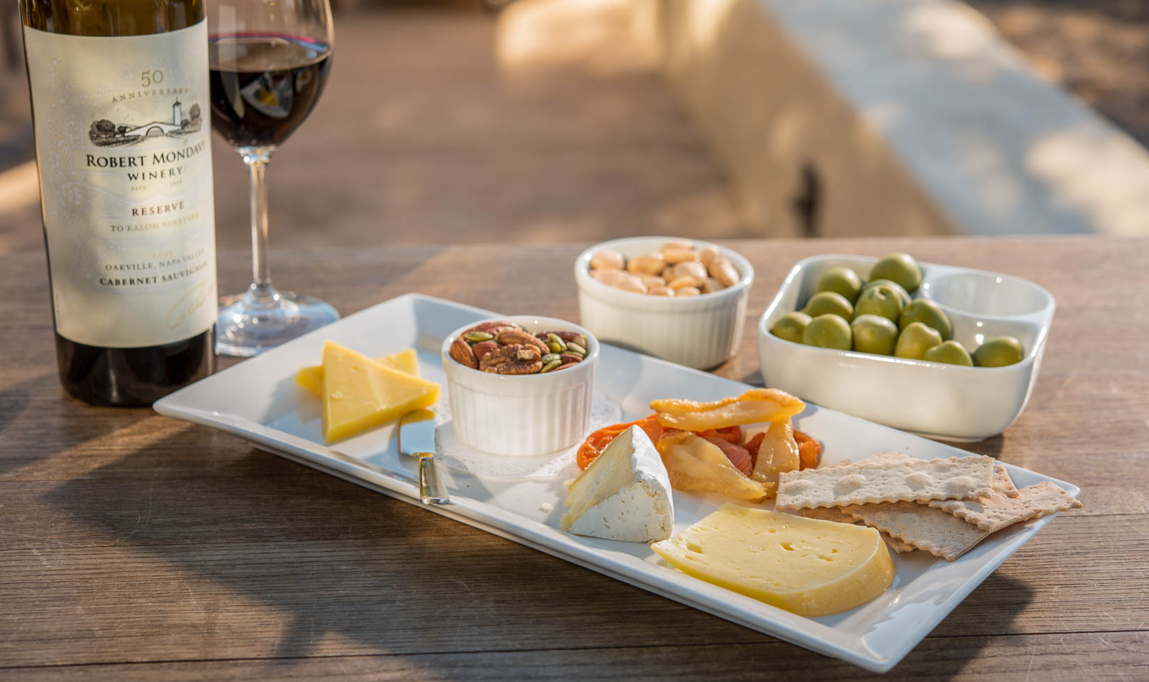 wine and cheese in the table with nuts and grapes