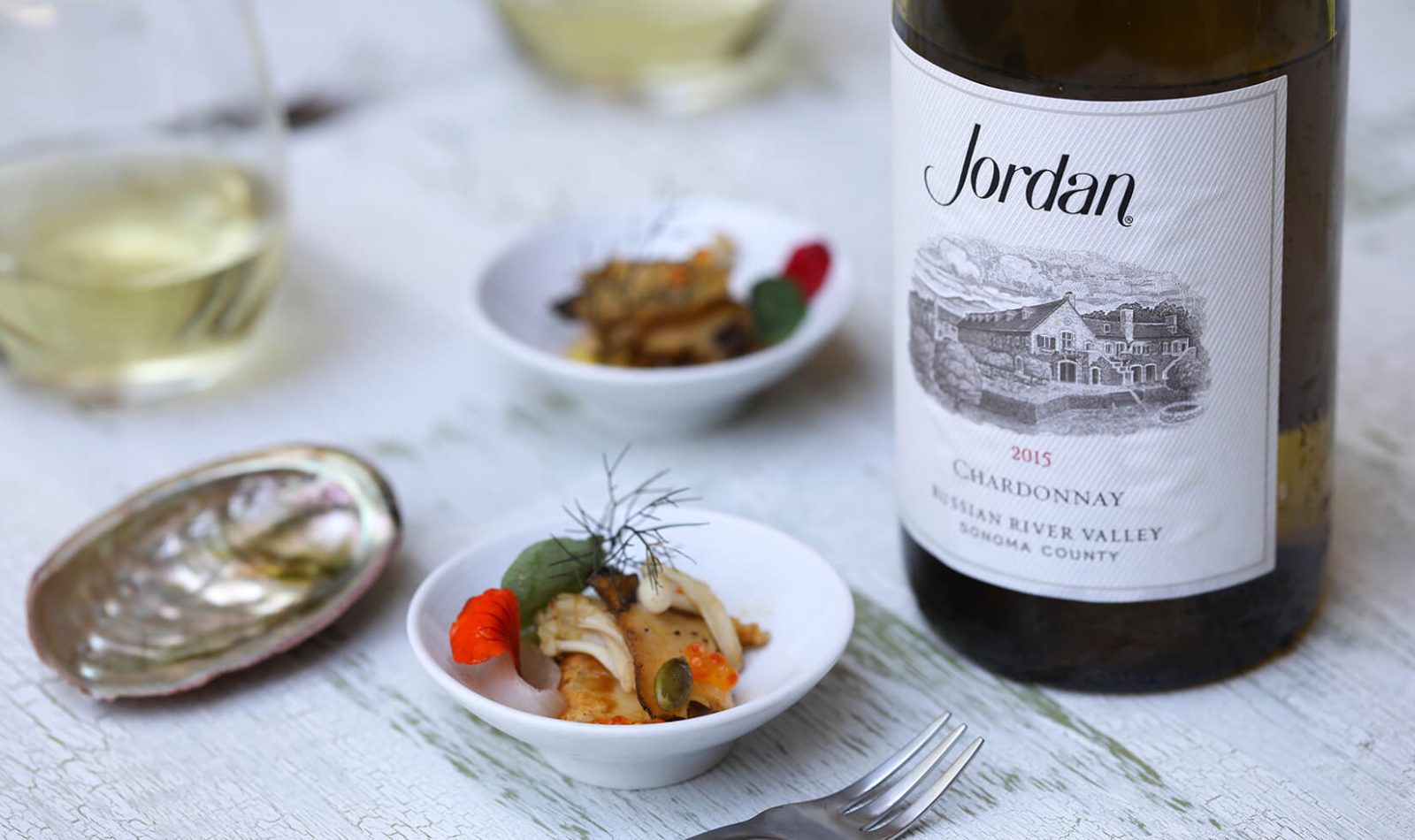 abalone food bite next to a bottle of Jordan Chardonnay