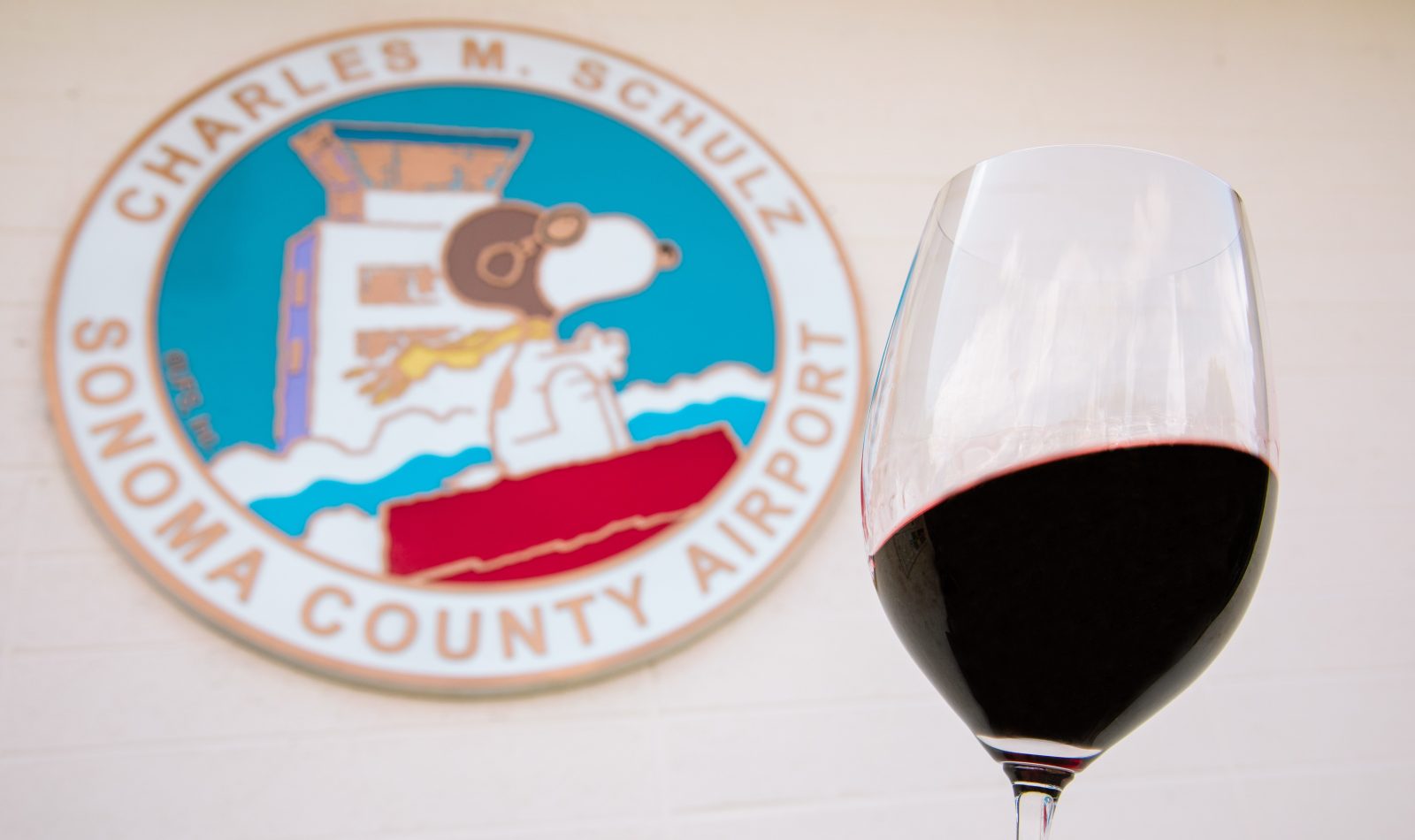 sign for Santa Rosa airport with a glass of red wine in the foreground