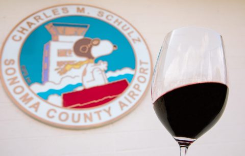 sign for Santa Rosa airport with a glass of red wine in the foreground