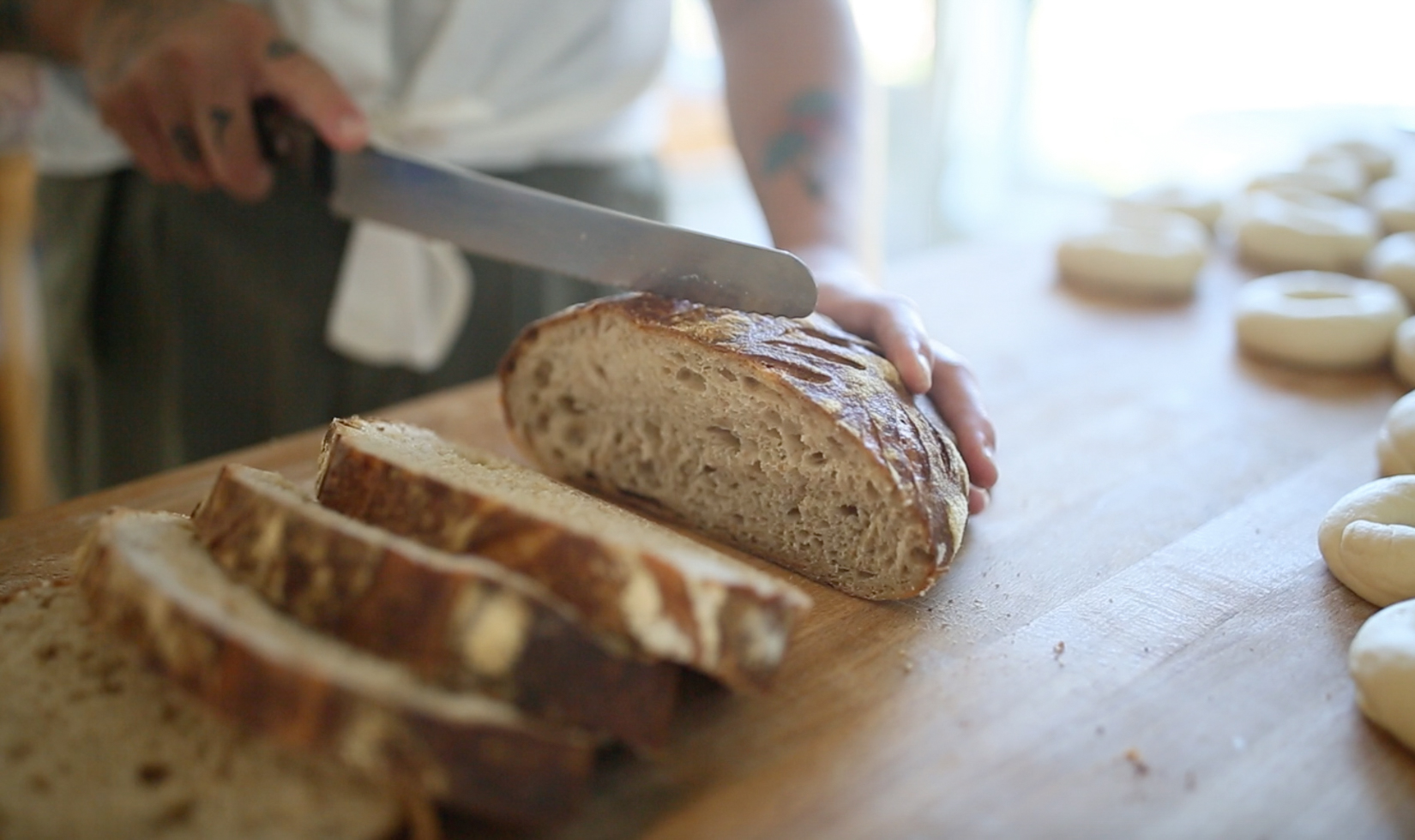 chef cutting bread with knife in kitchen; Quail & Condor Healdsburg restaurants
