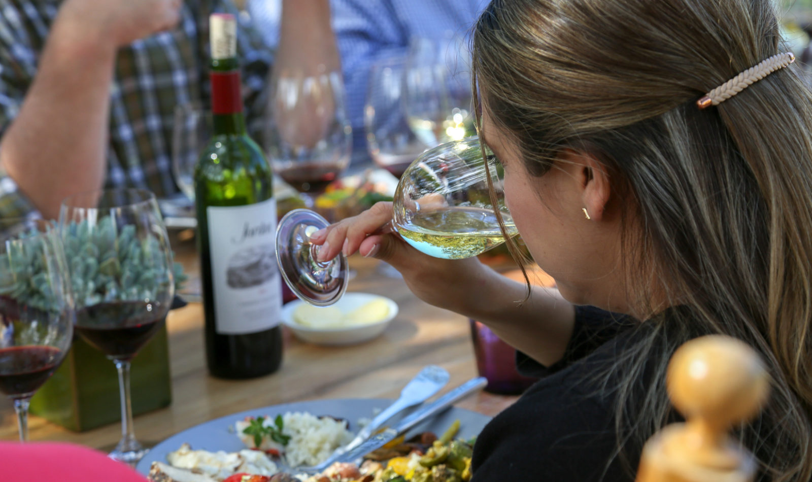 woman holding a glass of chardonnay to her nose at the lunch table