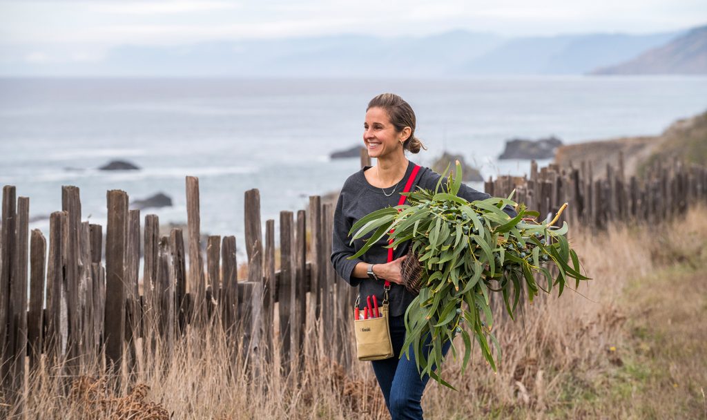 Jordan Winery Director of Hospitality Nitsa Knoll walking near the coastline with foraged plants in her hands.