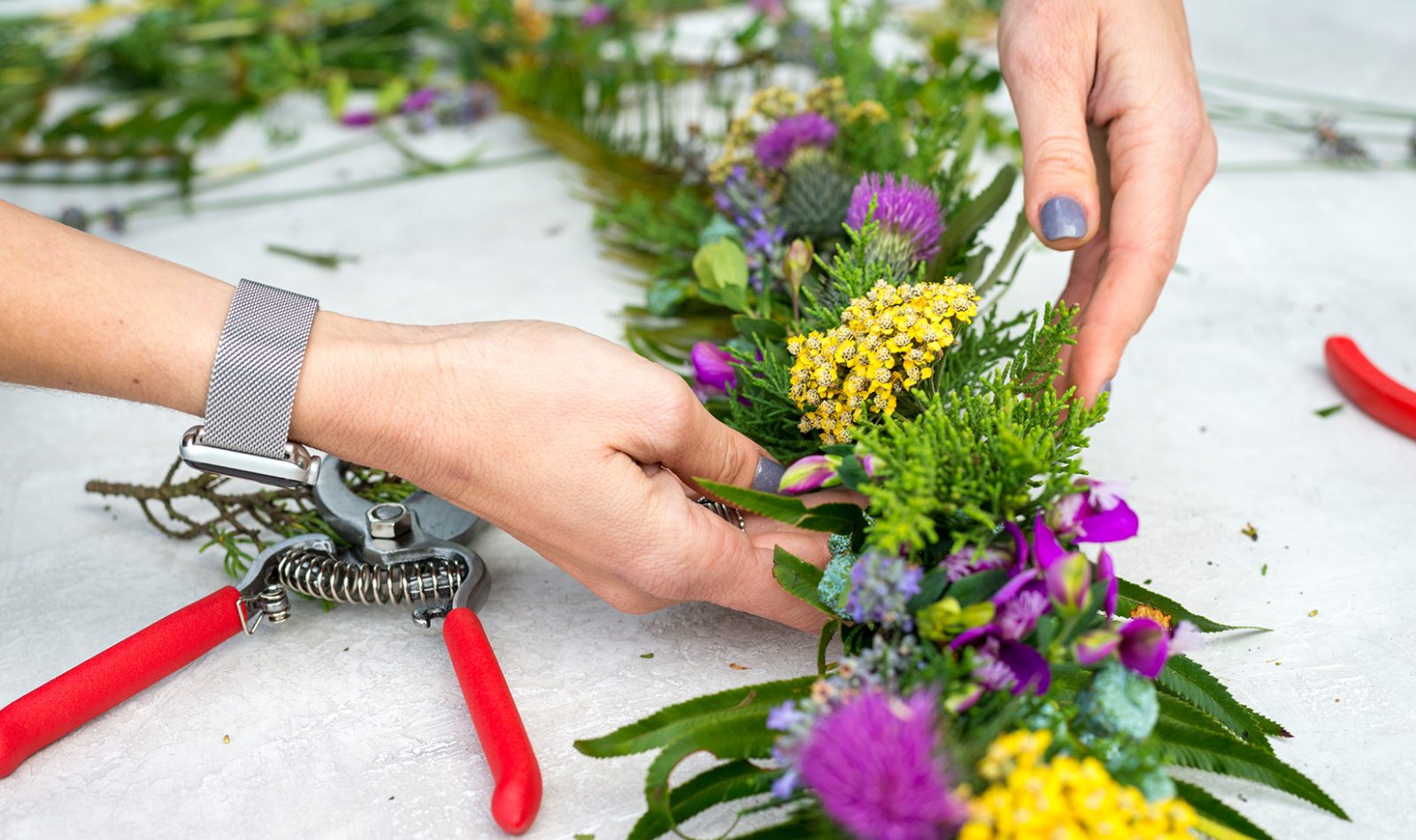 Close-up image of hands placing a yellow flower into a table garland.