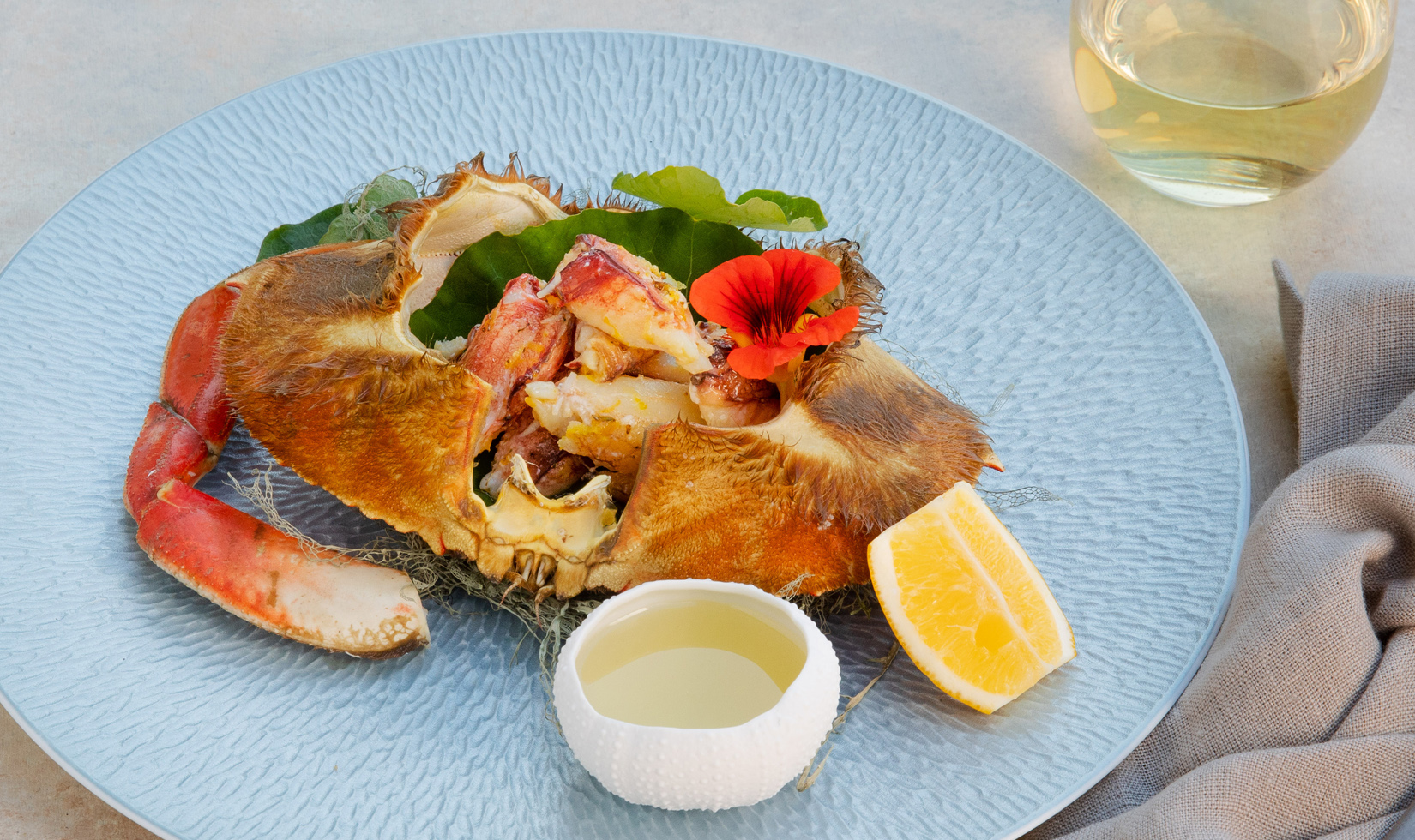 Dungeness crab with chardonnay drawn butter on blue plate with Jordan chardonnay glass