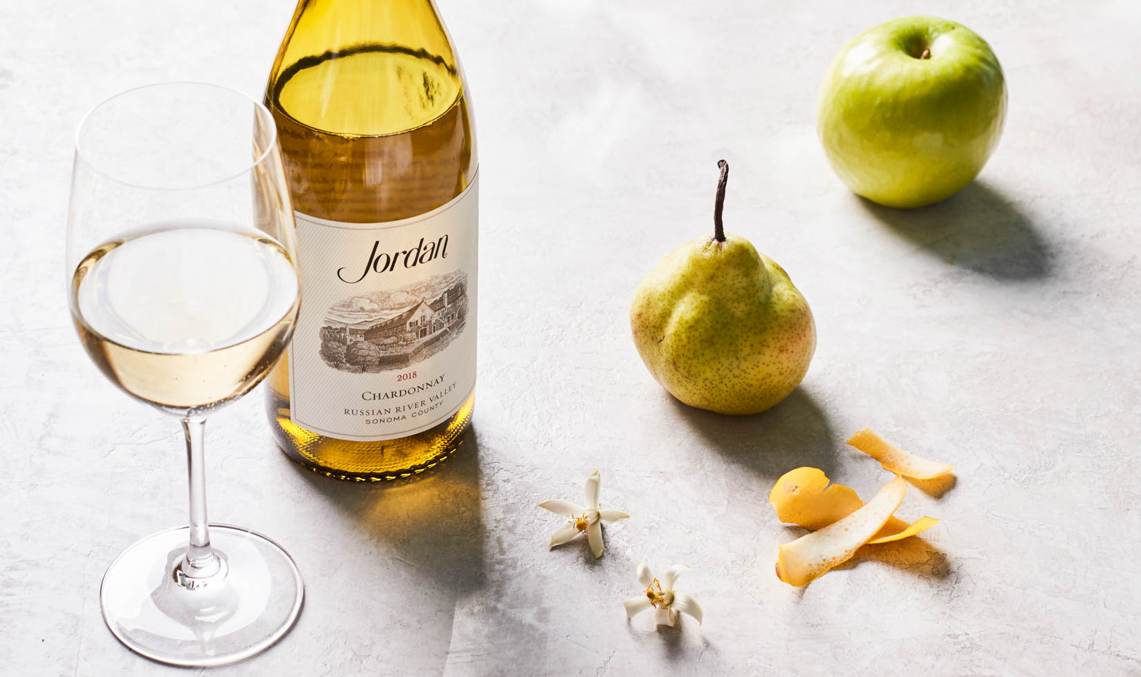 Jordan Winery 2018 Chardonnay next to a pear and a green apple