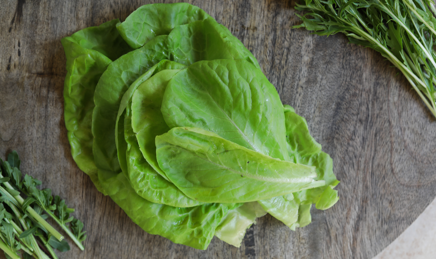 close up of tom thumb lettuce leaves on wooden board