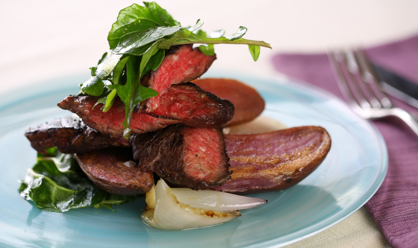 jordan winery close up of skirt steak with fingerling potatoes on blue plate with arugula