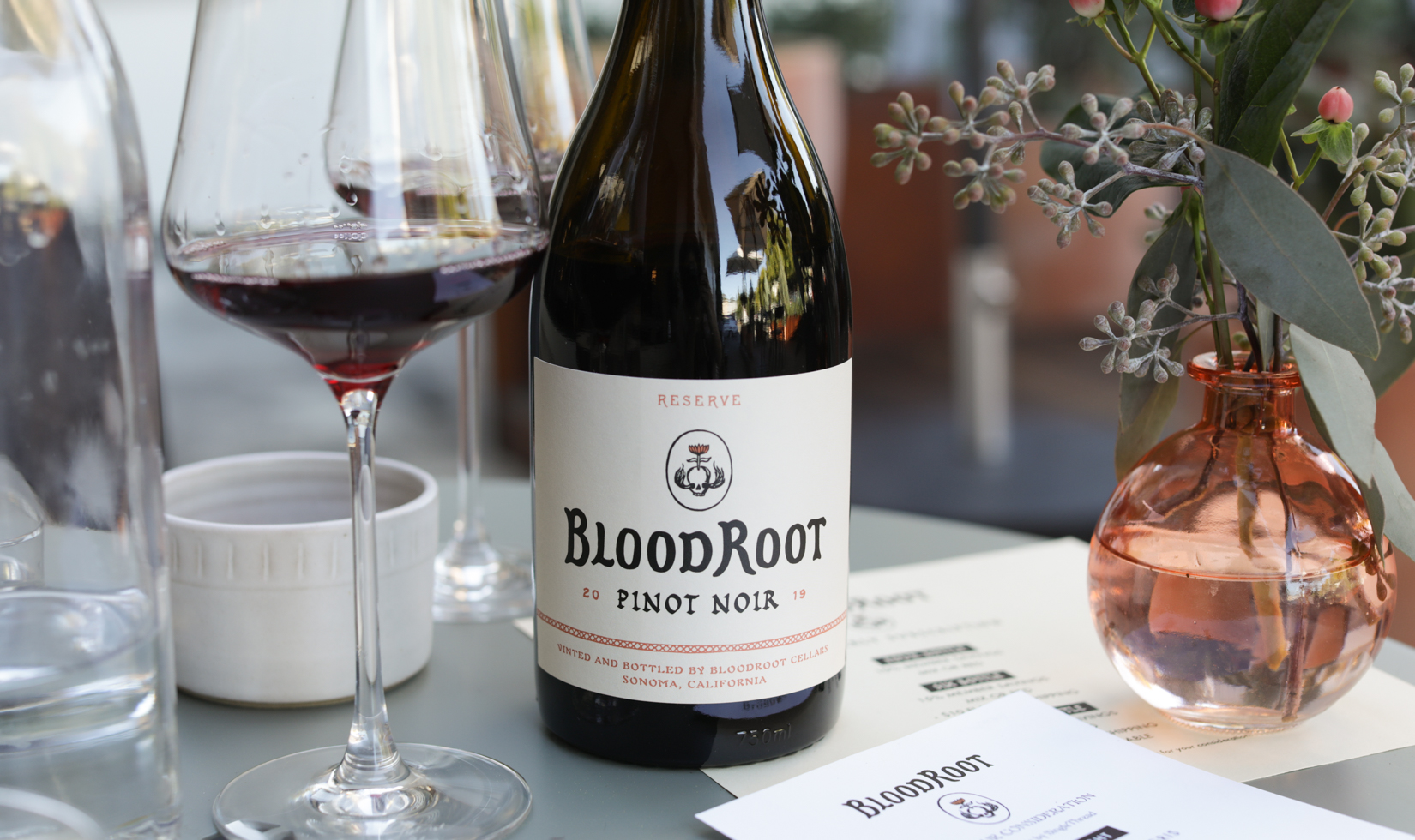bloodroot pinot noir wine bottle with glass of wine on a table