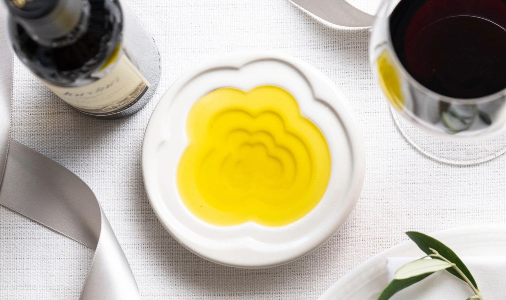 terraced dish filled with olive oil on table with white tablecloth