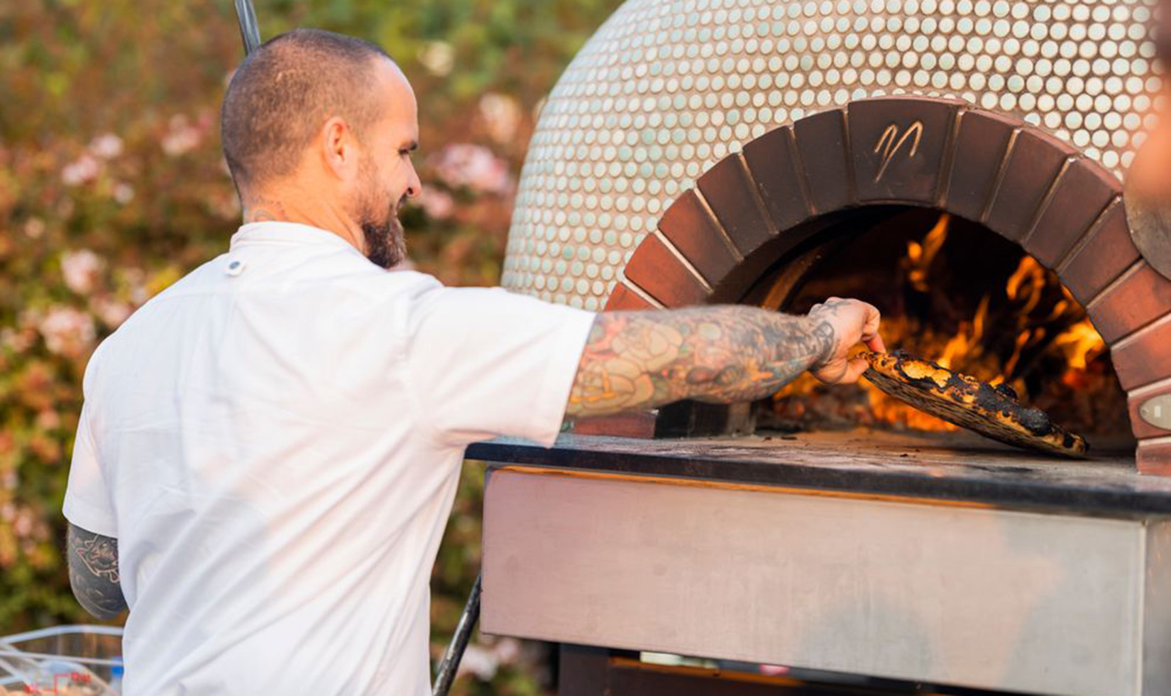 chef cooking pizza in a wood-fired oven