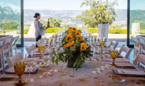 Long table set in glass pavilion atop hill for Sunset Supper.