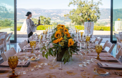 Long table set in glass pavilion atop hill for Sunset Supper.