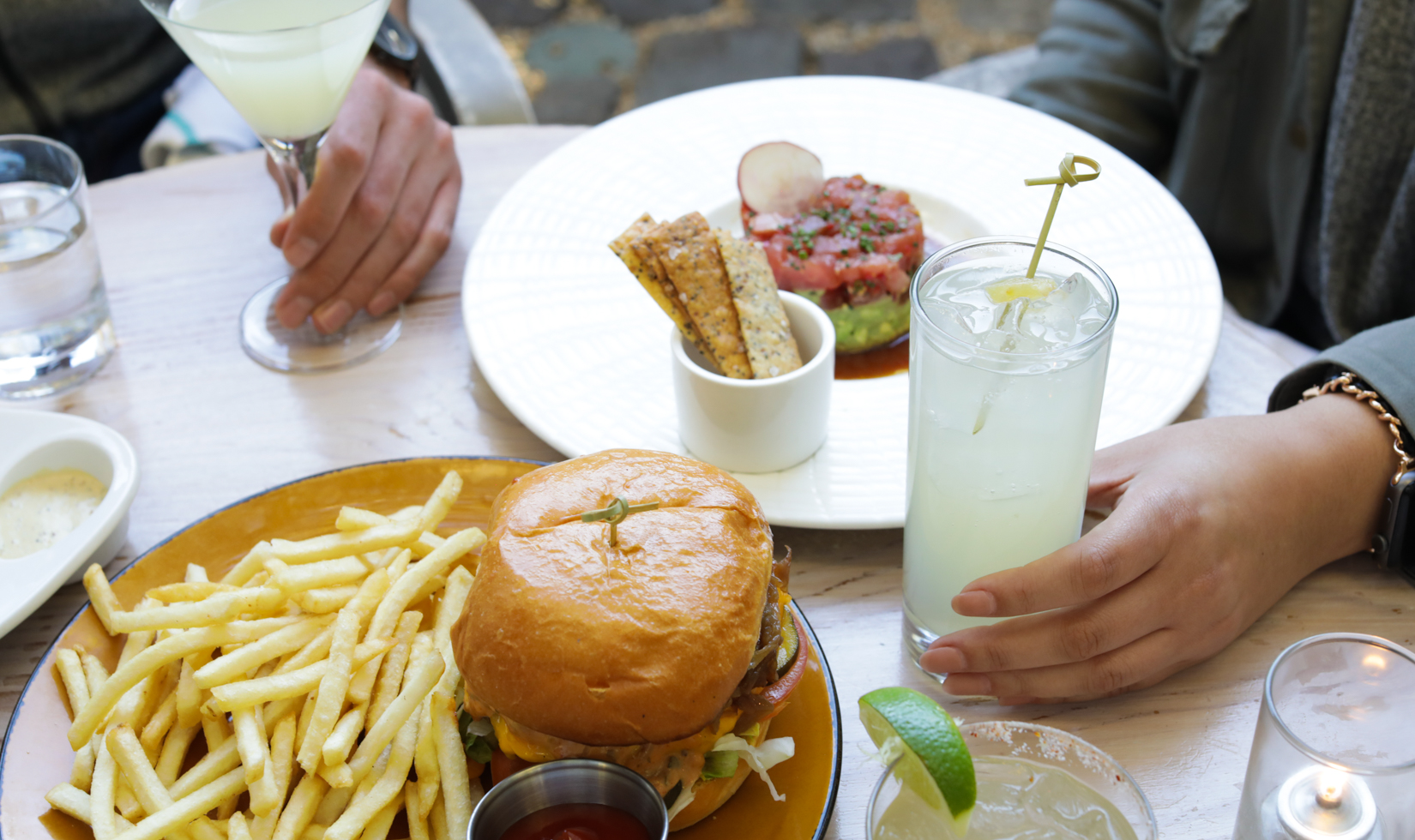 burger with french fries and cocktails in a restaurant courtyard patio