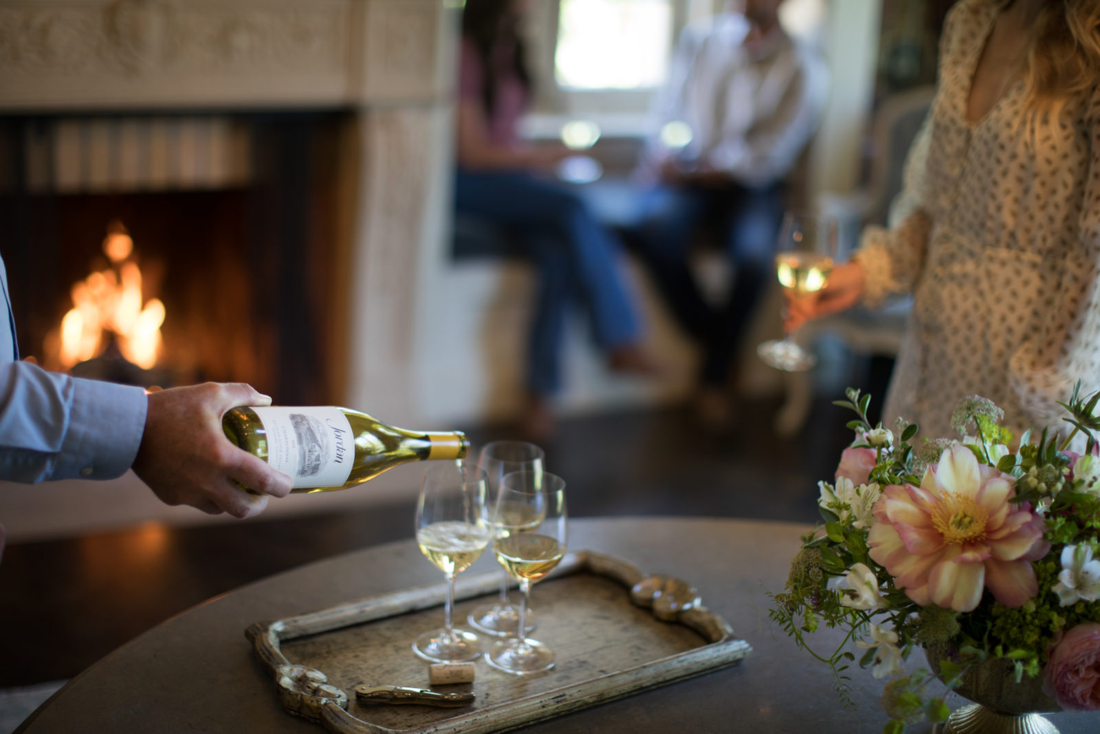 chardonnay pouring in wine glass with fireplace in the background