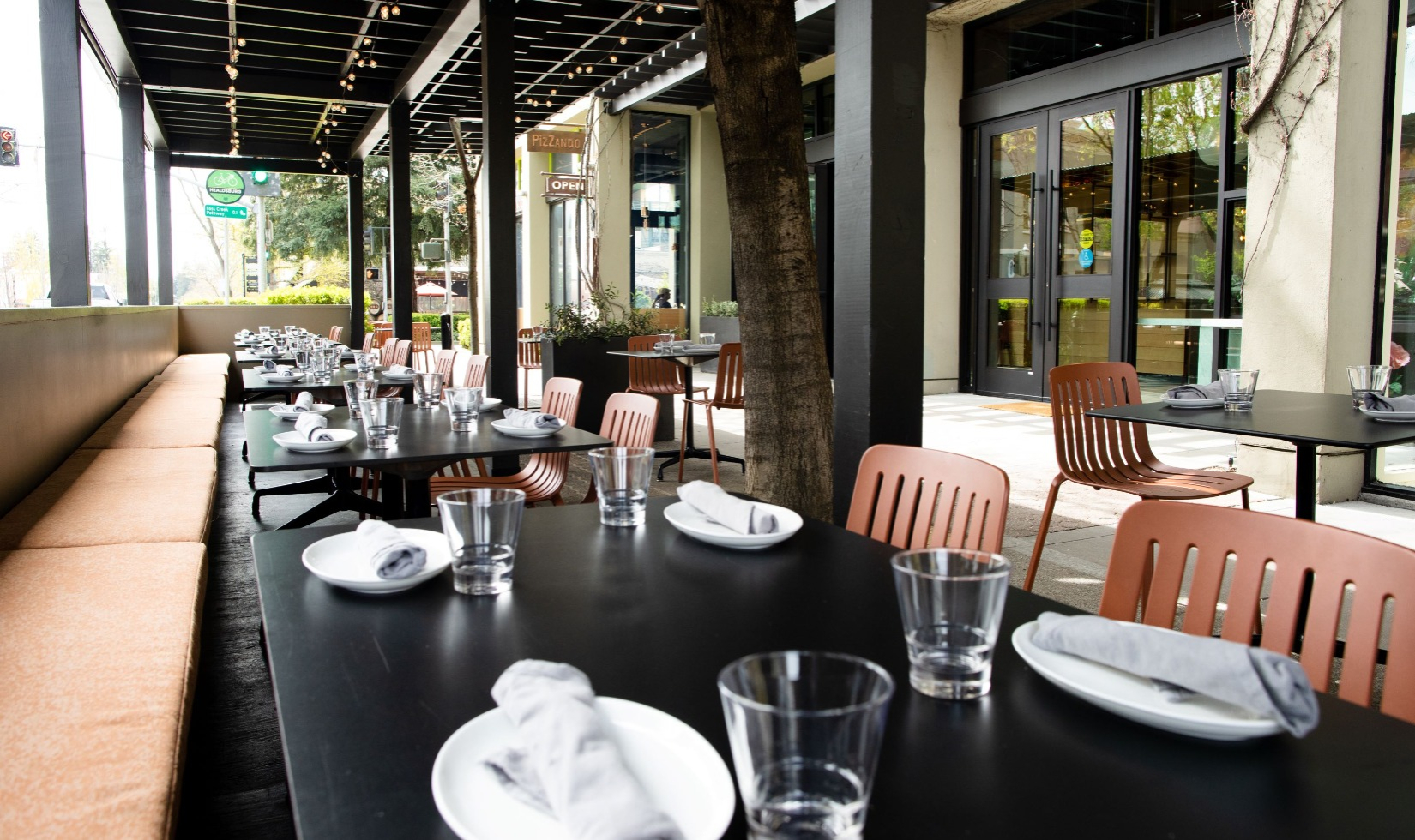 restaurant tables on outdoor dining spacing across sidewalk from pizzando restaurant main entrance