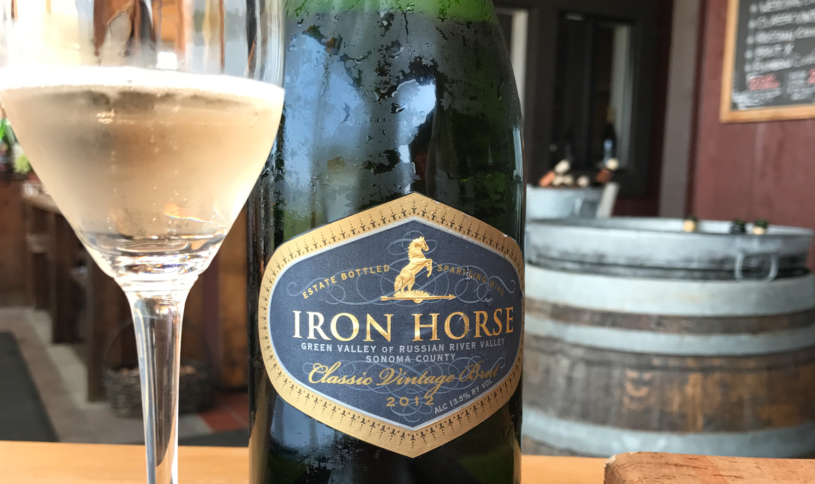 close up of sparkling wine label with barrel in the background