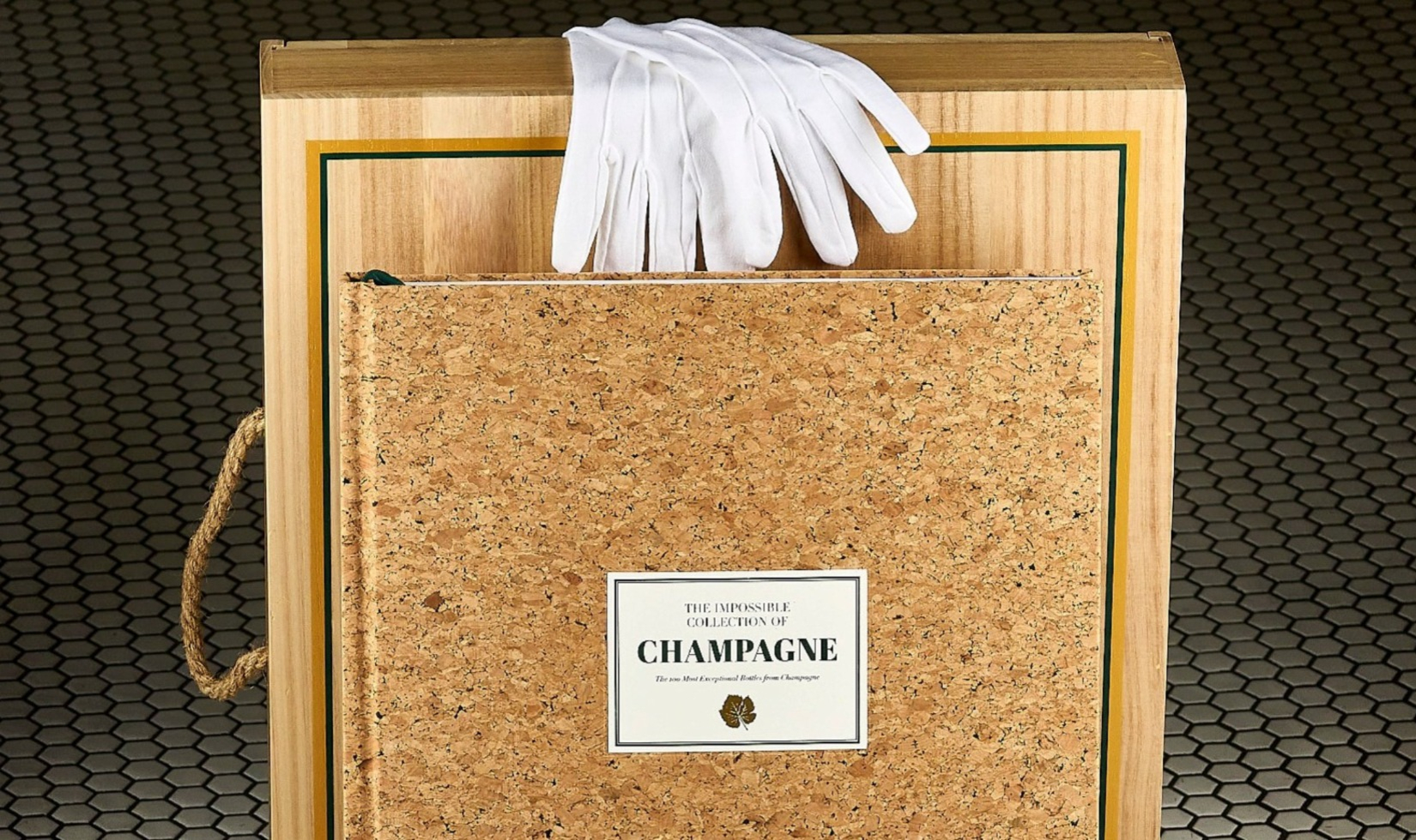 Luxury book with cover made of cork in front of wooden gift box with white reading gloves on top.