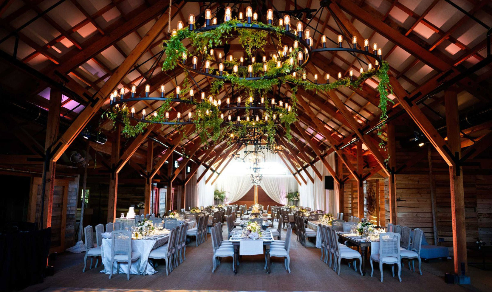 Dining room at winery with chandeliers and wooden beam across vaulted ceiling 