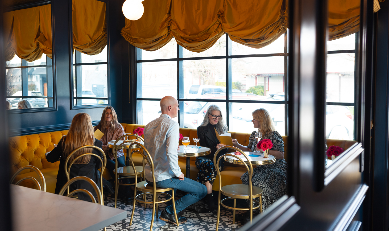 group of guests sitting in french-inspired restaurant with yellow drapes and bistro-style seating