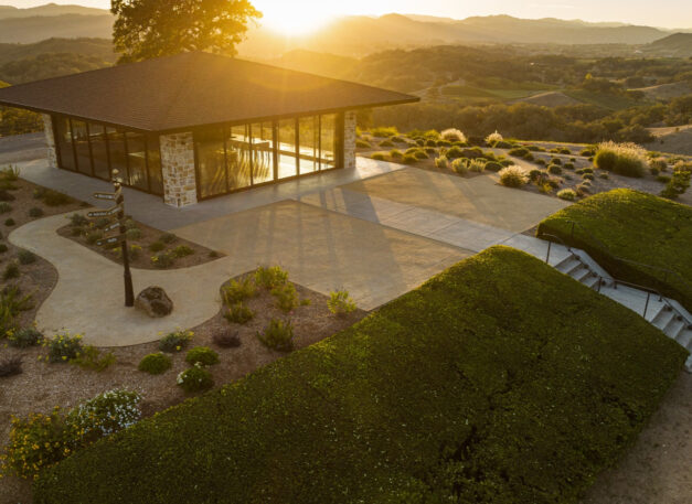 Modern glass building on hilltop overlooking vineyards