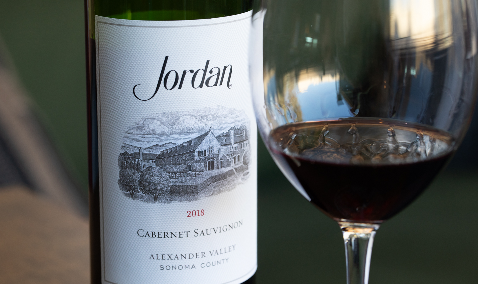 close up of jordan cabernet wine label and glass of red wine
