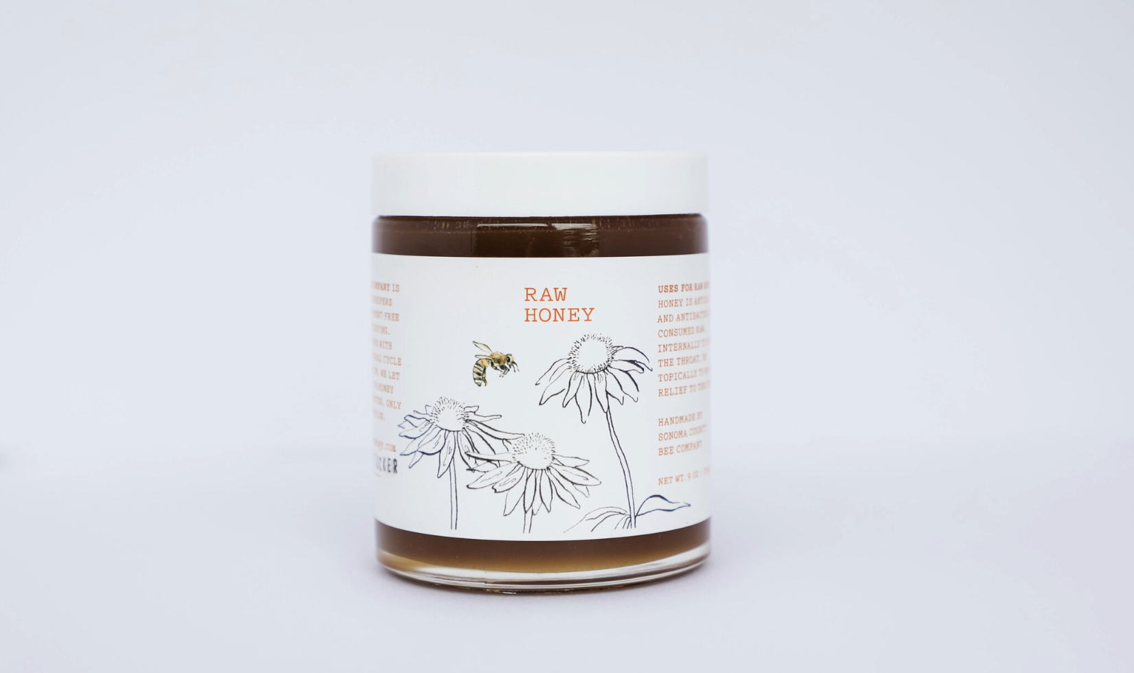 cannister of raw honey in front of white backdrop