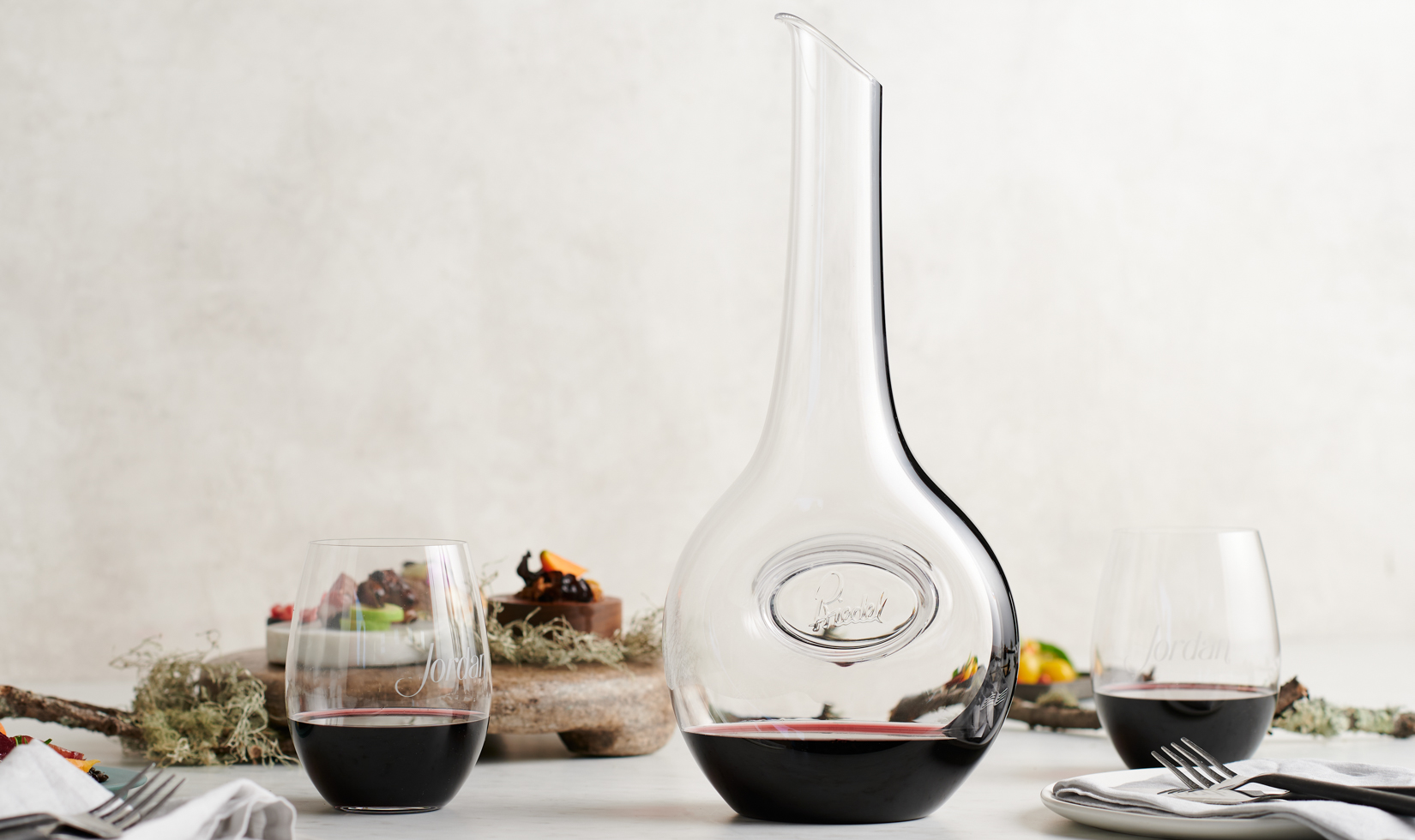 glass decanter with two stemless wine glasses on white table and background 