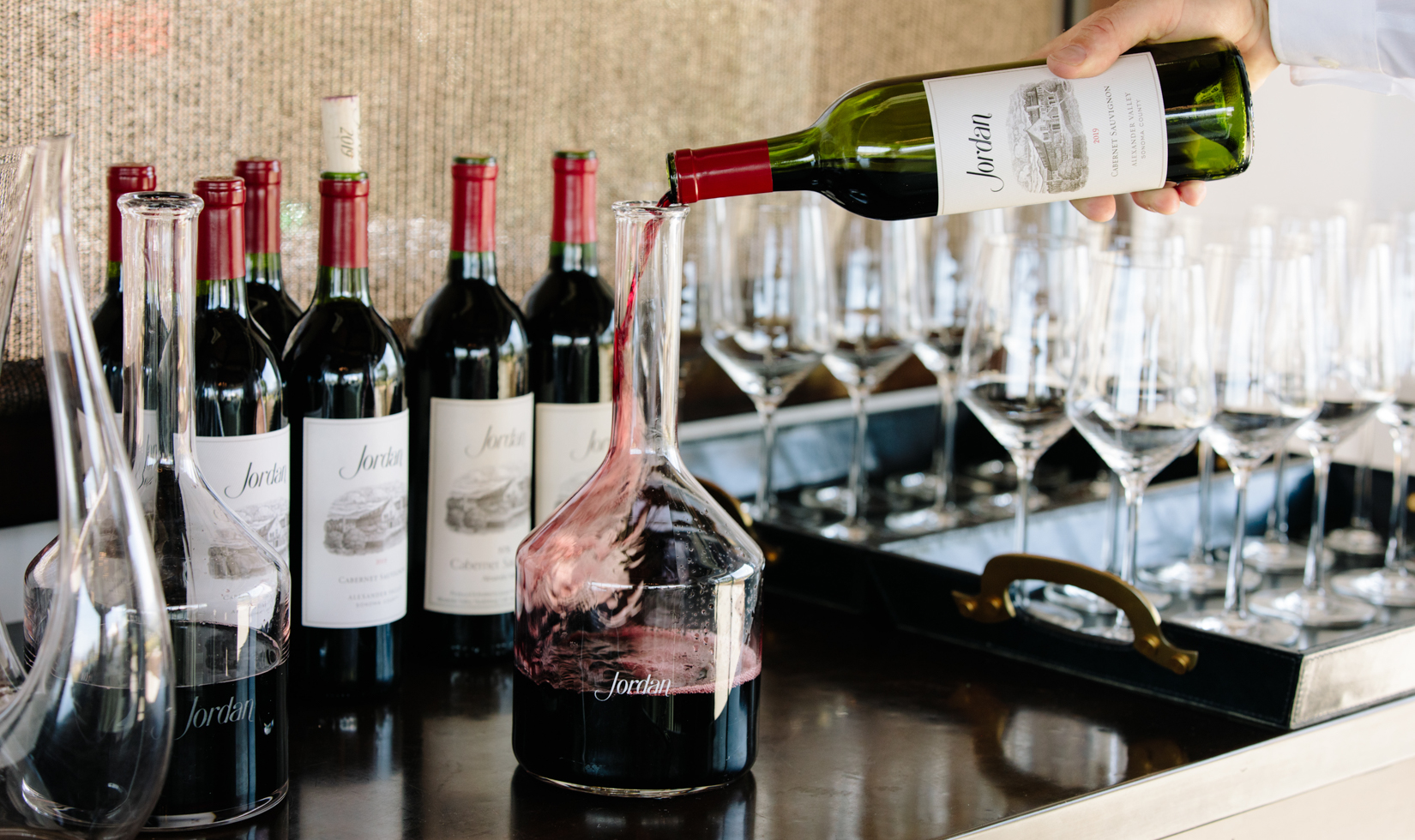 sommelier pouring bottle of cabernet into a decanter 