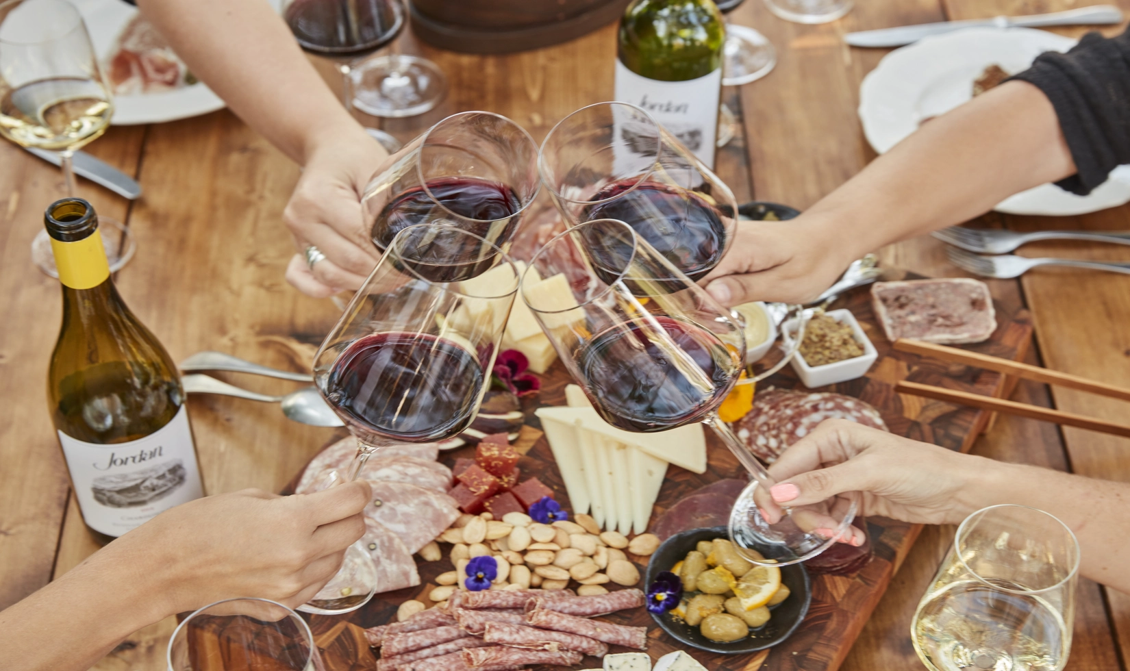Group of four people toasting their wine together in a table