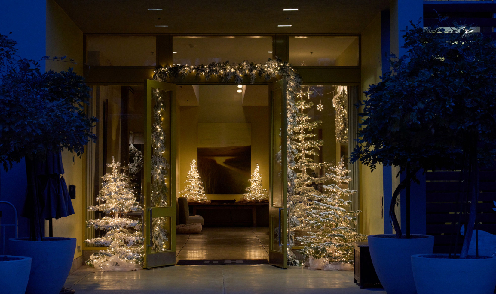 the entrance to the hotel healdsburg lobby decorated with small white christmas trees and garland
