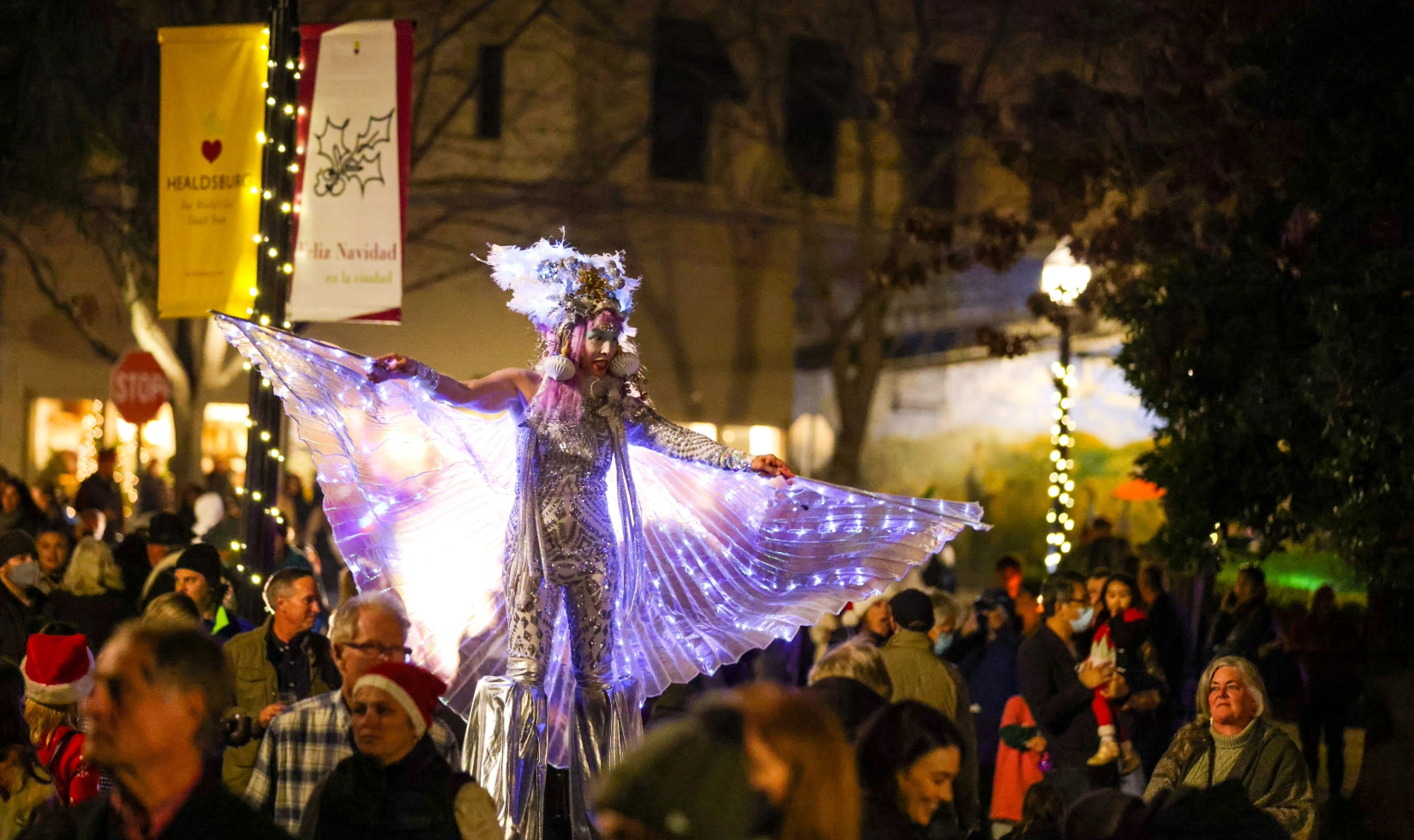 Christmas parade on streets of Healdsburg with performer in festive costume on stilts